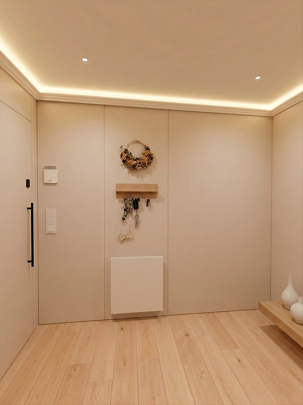 Casa Iván: recibidor con paneles lisos a medida, puerta enrasada y luz indirecta perimetral en el techo